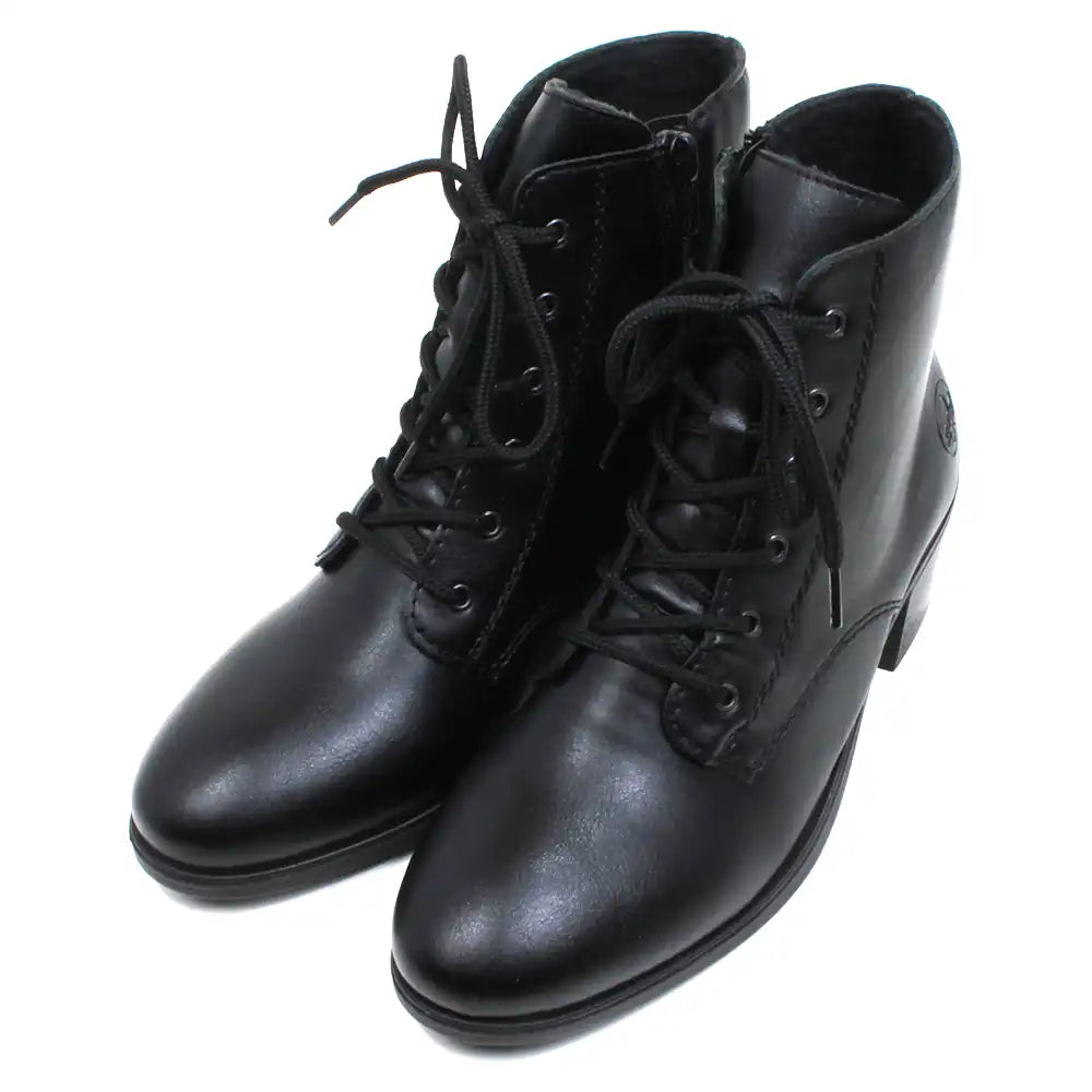 Rieker Victorian styled laced ankle boots with zip up fitting. Black with almond toes and medium heels. Embossed Rieker logo on heels. Angled view.