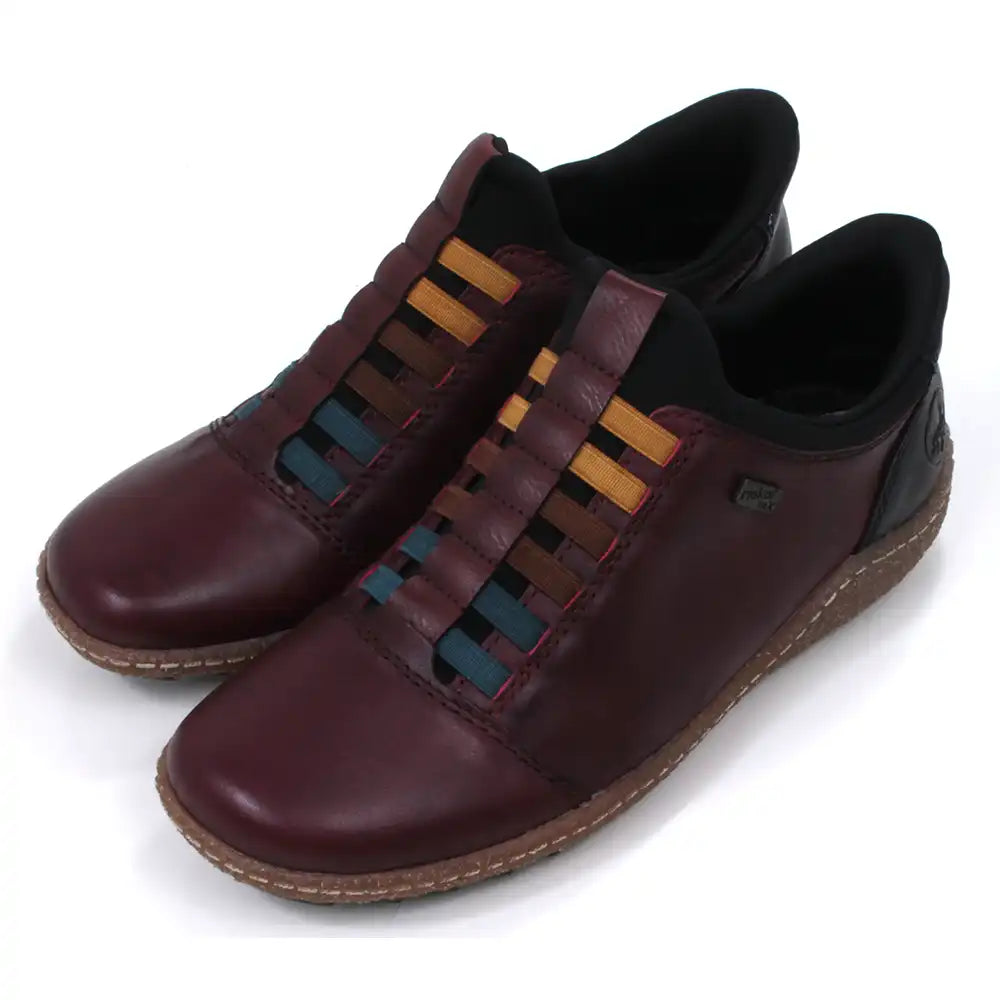Pair of maroon leather shoes with multicolored striped design on a white background. Angled view.