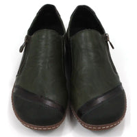 Pair of dark green leather shoes with zips on a white background. Front view.