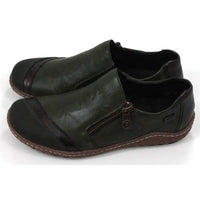 Pair of dark green leather shoes with zips on a white background. Side view.