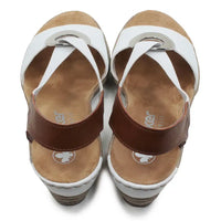 White and tan sandals with silver circular decorative detail.
