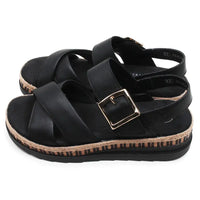 Black sandal with a gold buckle on a white background