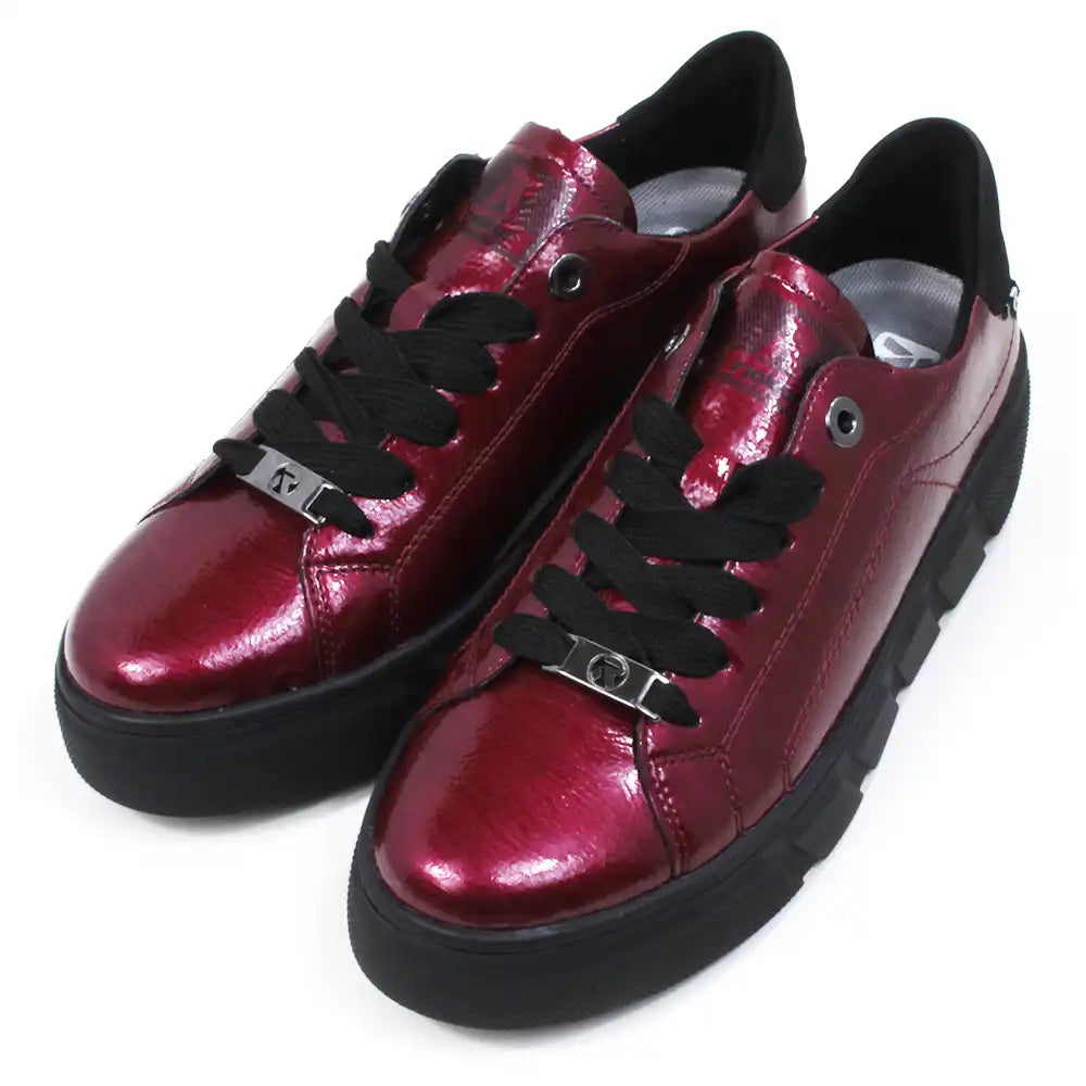 Pair of patent red shoes with black laces on a white background.