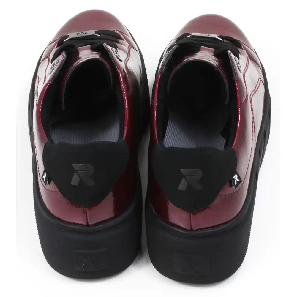 Pair of patent red shoes with black laces on a white background.