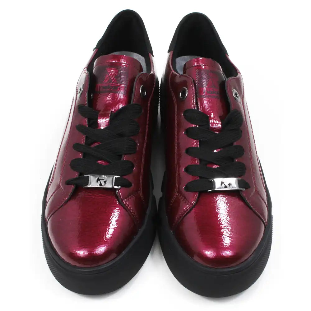 Pair of patent red shoes with black laces on a white background.