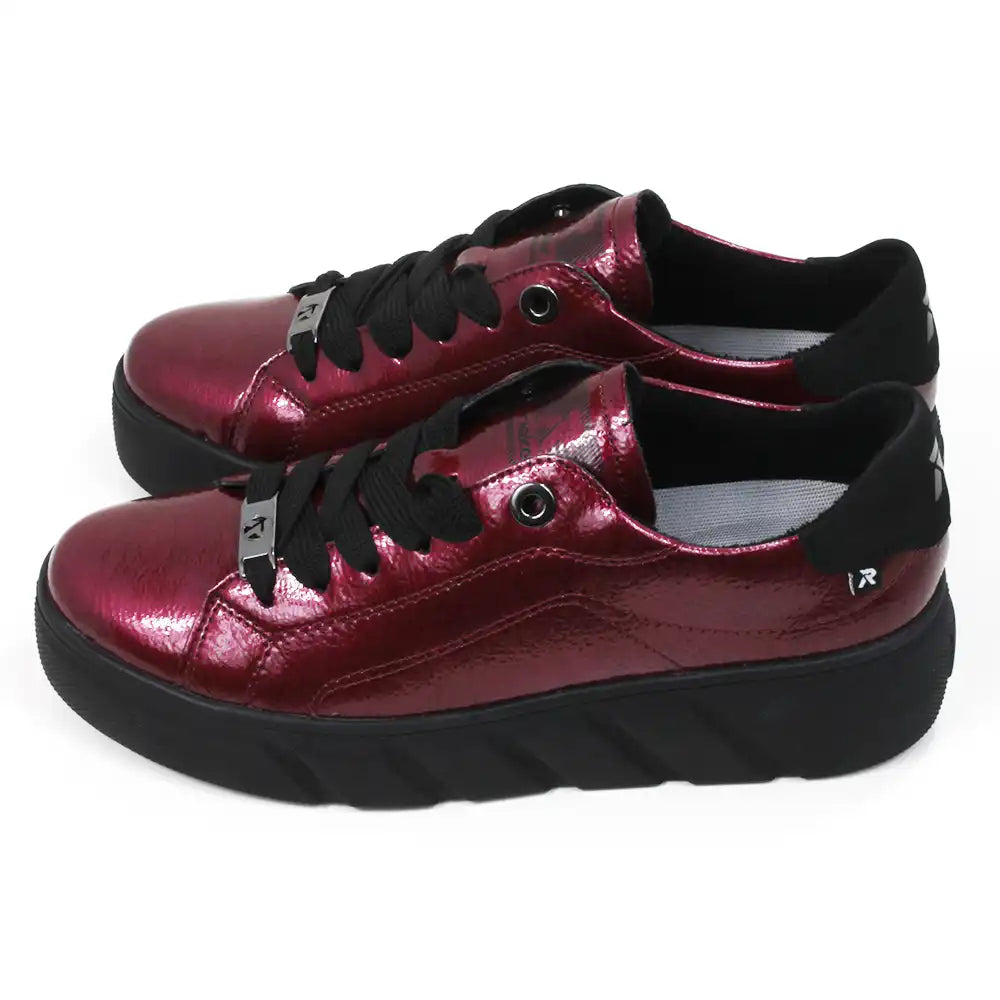 Pair of patent red shoes with black laces on a white background.