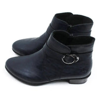 Rieker navy blue ankle boots with almond shaped toes. Strap detail around lower ankle. Zip fastening on the inside of the botts. Mid heel. Side view.