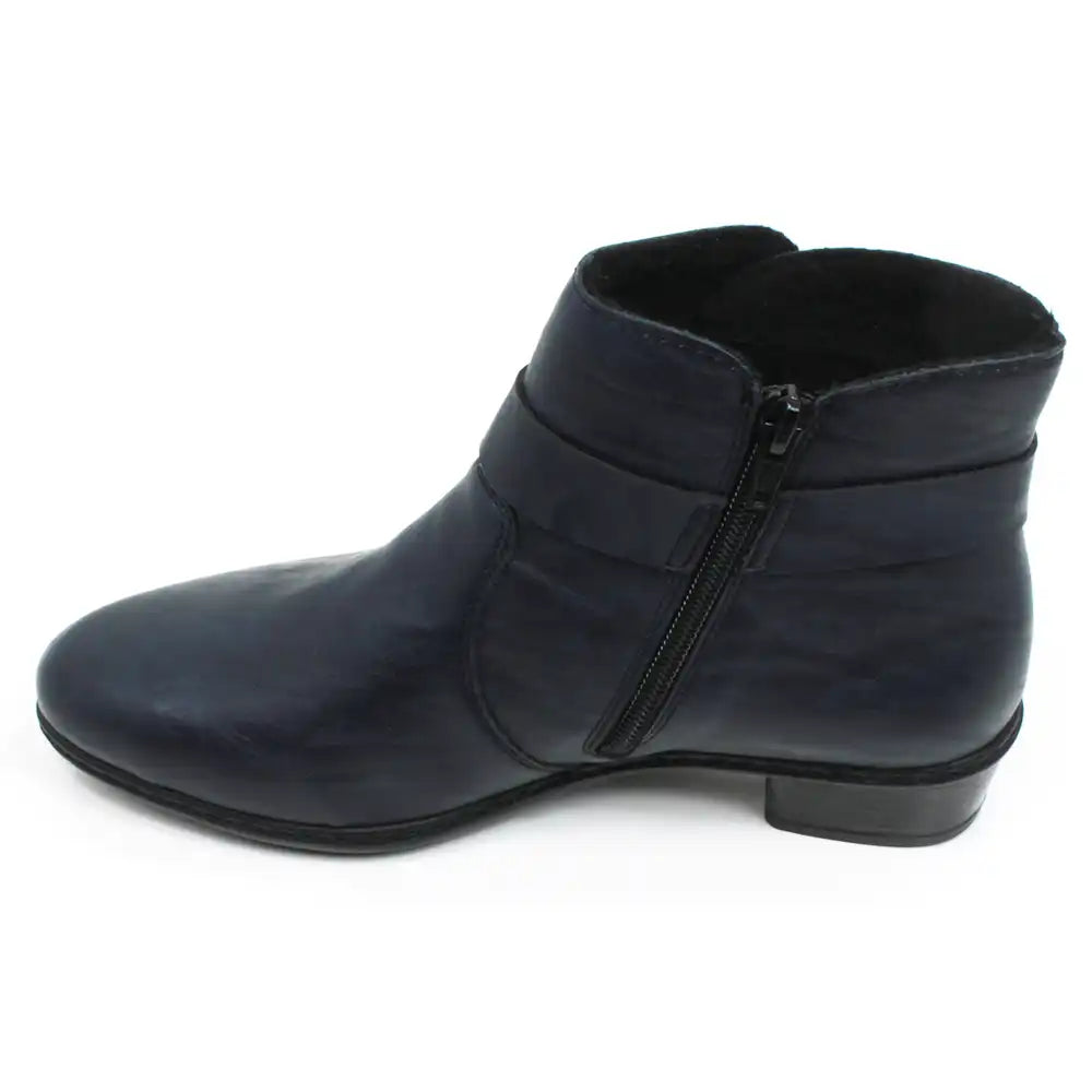 Rieker navy blue ankle boots with almond shaped toes. Strap detail around lower ankle. Zip fastening on the inside of the botts. Mid heel. Single boot view showing the zip fastening.