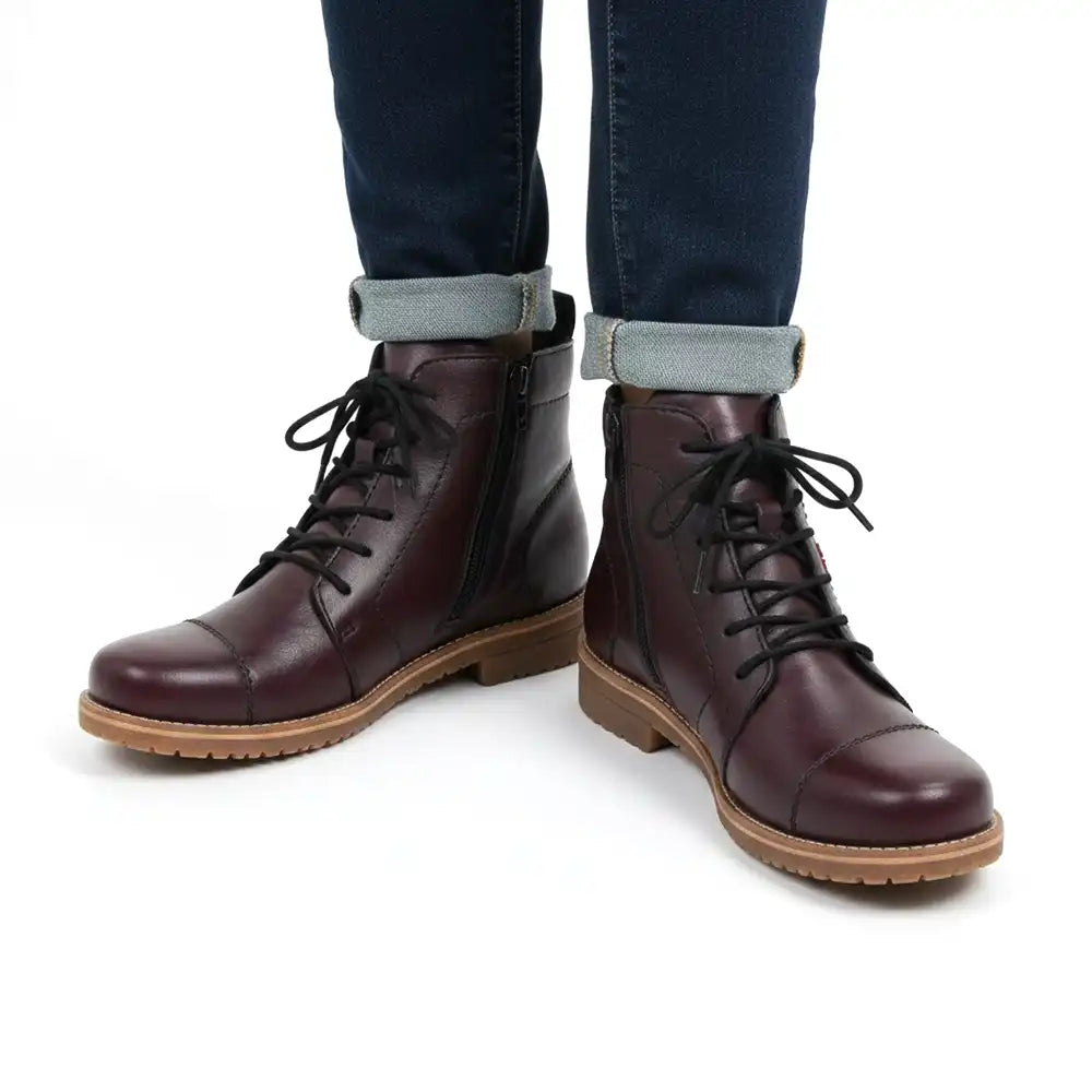 Claret lace up boots being worn with jeans in a white studio.