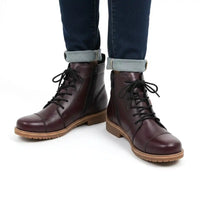 Claret lace up boots being worn with jeans in a white studio.