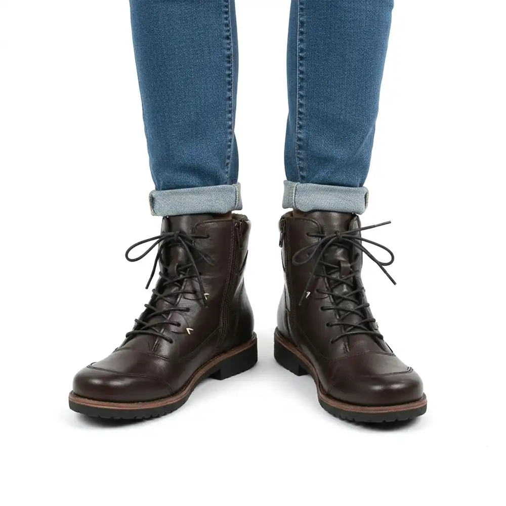 A pair of dark brown leather lace-up ankle boots worn with cuffed blue jeans, shown from the front against a plain white background.