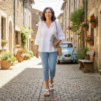 Woman walking down a quaint street with a vintage car and decorative plants in the background