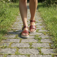 Brown sandals worn on a stone path with grass on either side