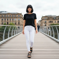 Young woman walking across a footbridge. She is wearing a black top, white jeans and black sandals.
