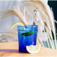 Blue glass with lemon slices on a wooden surface with blurred natural background