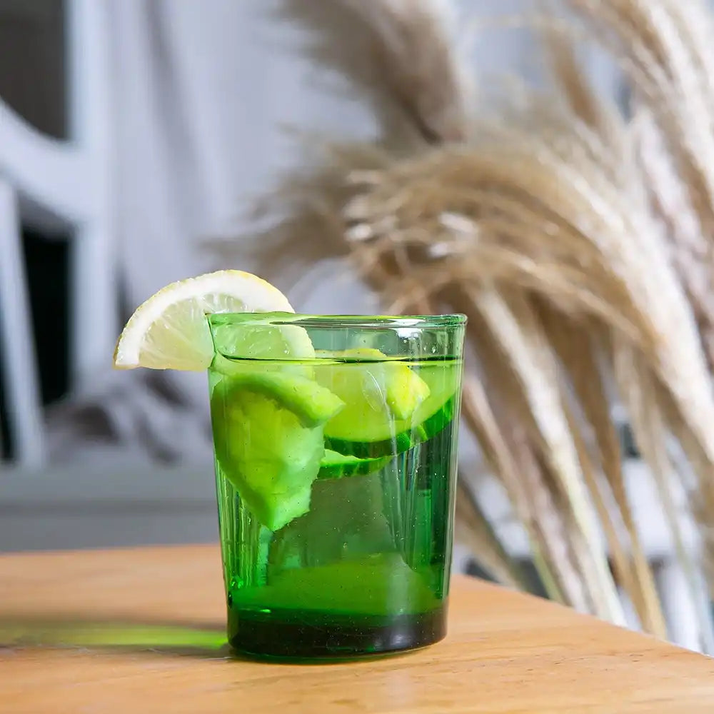 Green cocktail with lime slices in a glass on a wooden table.