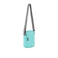 Turquoise crossbody bag with a gray strap on a white background