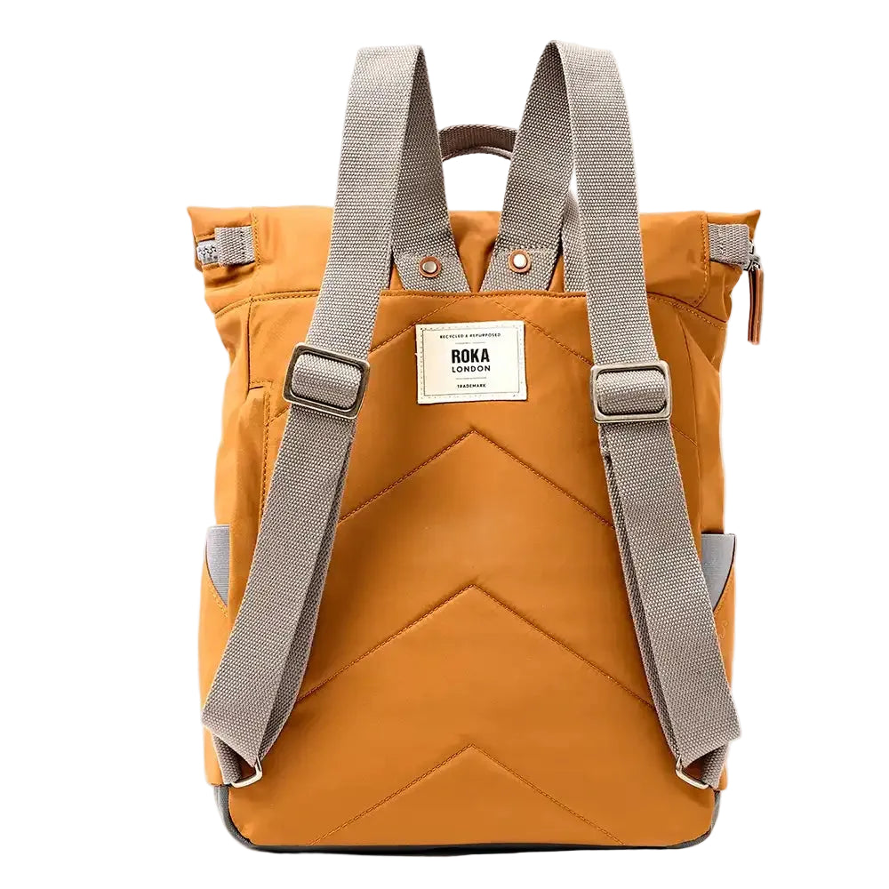 Rear view of a caramel backpack with padded chevron stitching and grey straps. ROKA label in white in middle. 
