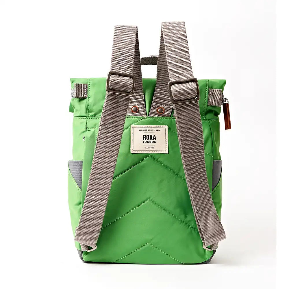 Rear view of a dark lime backpack with padded chevron stitching and grey straps.ROKA label in white in middle. .