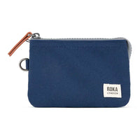 Blue zippered pouch with Roka London label on a white background