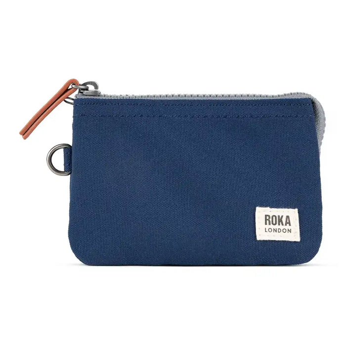 Blue zippered pouch with Roka London label on a white background