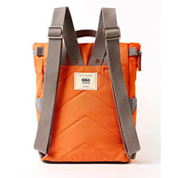 A back view of an orange quilted canvas backpack with dark grey adjustable shoulder straps and a white brand label on the front, shown against a plain white background.