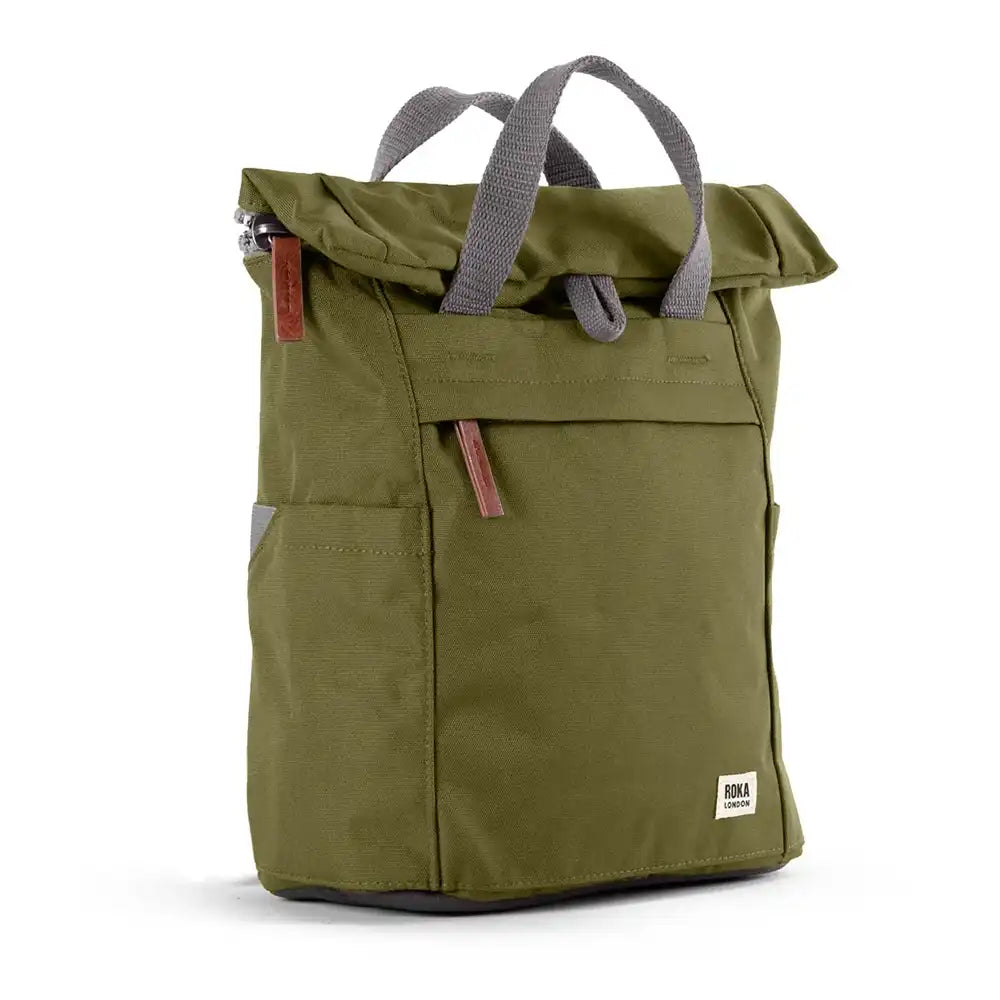An olive green roll-top backpack with grey webbed handles, a front zippered pocket, and small brown leather accents, shown on a clean white background.