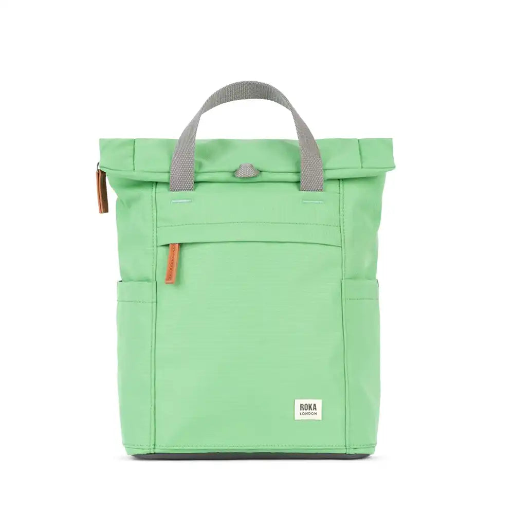 Roka pale green backpack with grey canvas straps and handles. Fold over zipped top opening. External zipped pocket. Open pockets on each side.