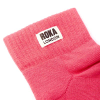 Close-up of a pink sock with a Roka London label on a white background