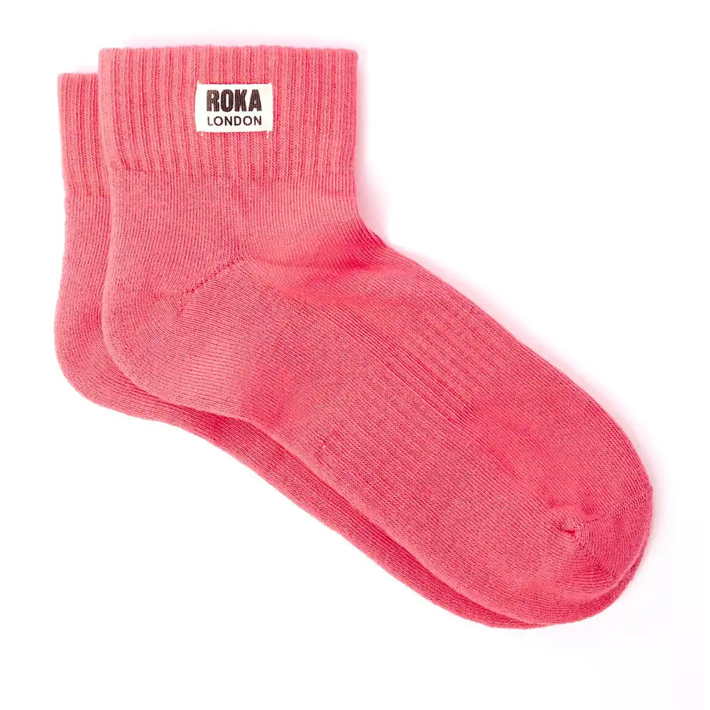 Pink socks with Roka London label on a white background