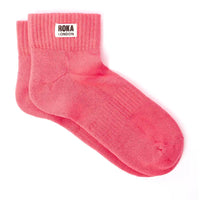 Pink socks with Roka London label on a white background
