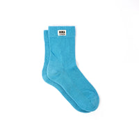 A pair of bright turquoise blue crew socks with a white brand label reading 'ROKA LONDON' on the cuff, displayed on a clean white background.