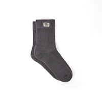 A pair of faded black crew socks with a small white brand label reading 'ROKA LONDON' on the cuff, shown against a plain white background.
