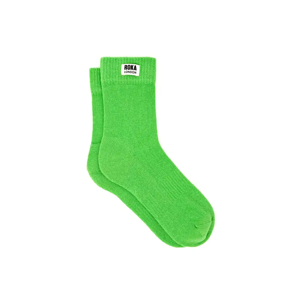 A pair of bright green crew socks with a small white brand label reading 'ROKA LONDON' on the cuff, shown against a plain white background.