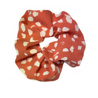 Orange scrunchie with white pattern on a white background