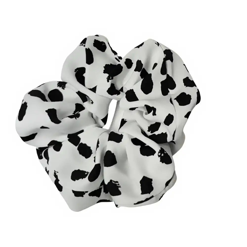 White scrunchie with black polka dot pattern on a white background