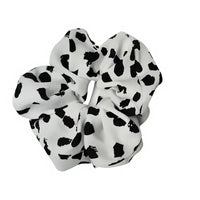 White scrunchie with black polka dot pattern on a white background