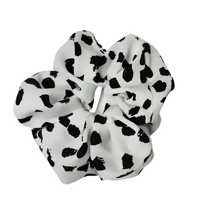 White scrunchie with black polka dot pattern on a white background
