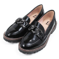 Pair of black patent faux leather loafers with a decorative buckle. Angled view.