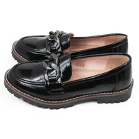 Pair of black patent faux leather loafers with a decorative buckle. Side view.