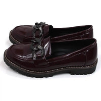 Shoes by Emma patent burgundy loafers with black chunky soles. Over the toes grey metal chain detail. Side view.