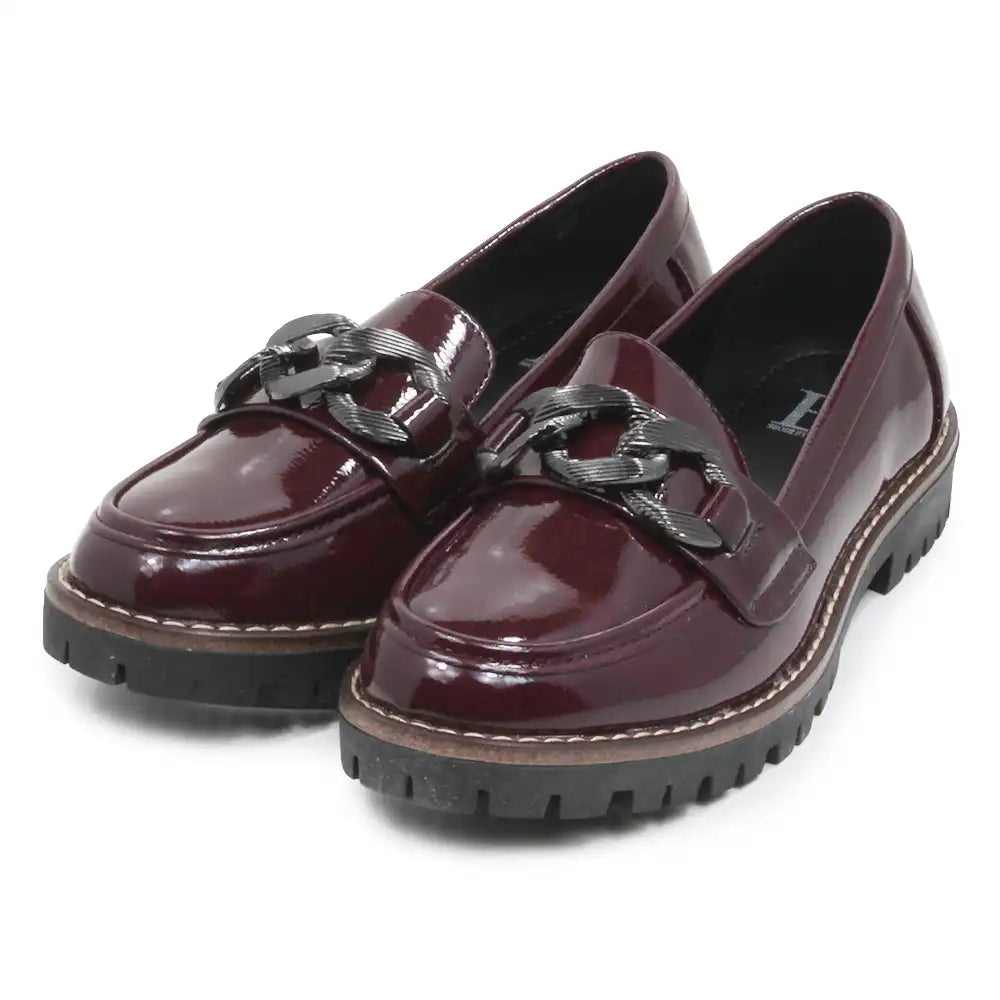 A pair of glossy burgundy patent leather penny loafers with chunky black chain strap details and black lug soles, shown on a white background.