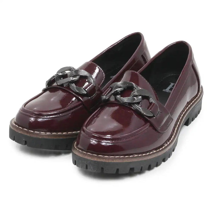 A pair of glossy burgundy patent leather penny loafers with chunky black chain strap details and black lug soles, shown on a white background.