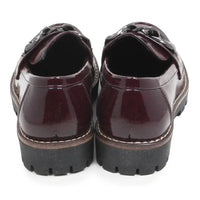 A pair of glossy patent leather loafers in deep burgundy, viewed from the back. They feature chunky black platform soles with white contrast stitching along the edge.