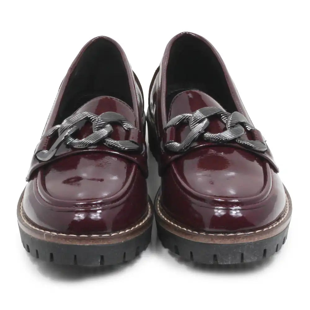 A pair of glossy burgundy patent leather loafers with chunky black chain details across the vamp and thick black lug soles, shown from a front-facing perspective on a white background.