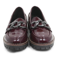 A pair of glossy burgundy patent leather loafers with chunky black chain details across the vamp and thick black lug soles, shown from a front-facing perspective on a white background.
