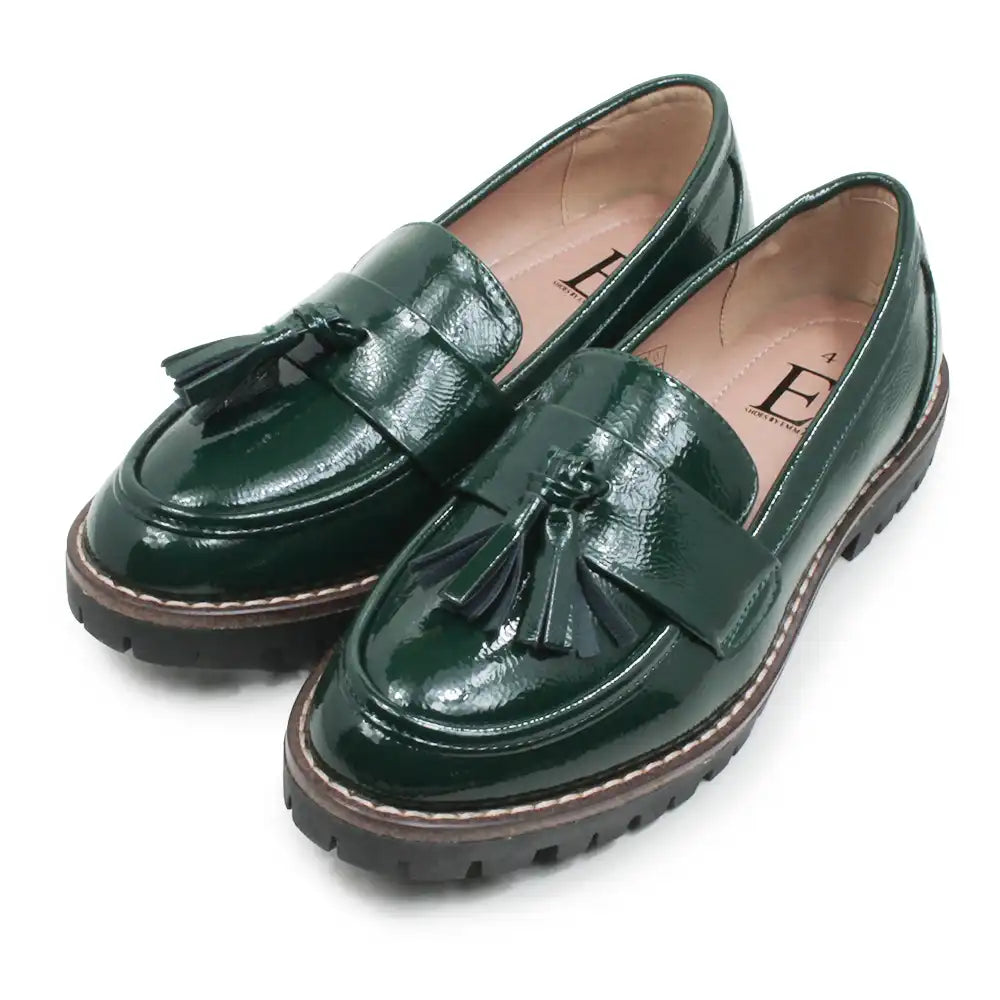 A pair of dark green patent leather tassel loafers with chunky black lug soles, displayed on a clean white background.