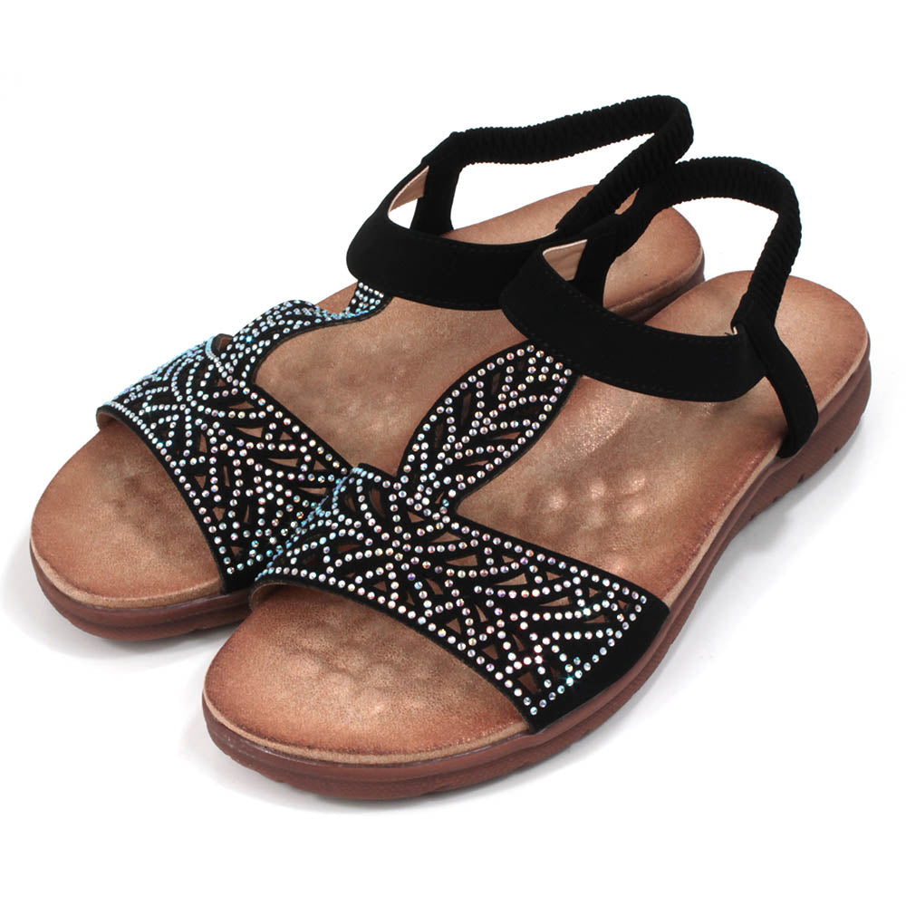 Black sandals decorated with diamantes. Elasticated black ankle strap. Tan, molded insoles. Angled view.