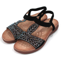 Emma black sandals decorated with diamantes. Elasticated black ankle strap. Tan, molded insoles. Angled view.