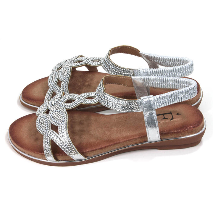 Silver, diamante covered sandals. Silver elasticated ankle straps. Tan coloured insoles. Silver trim around the soles. Side view.